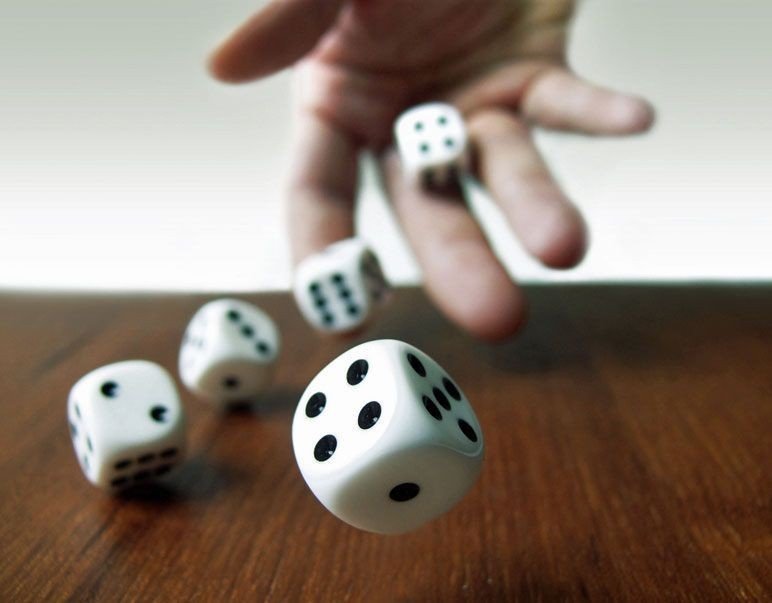 Hand rolling 5 dice on a table