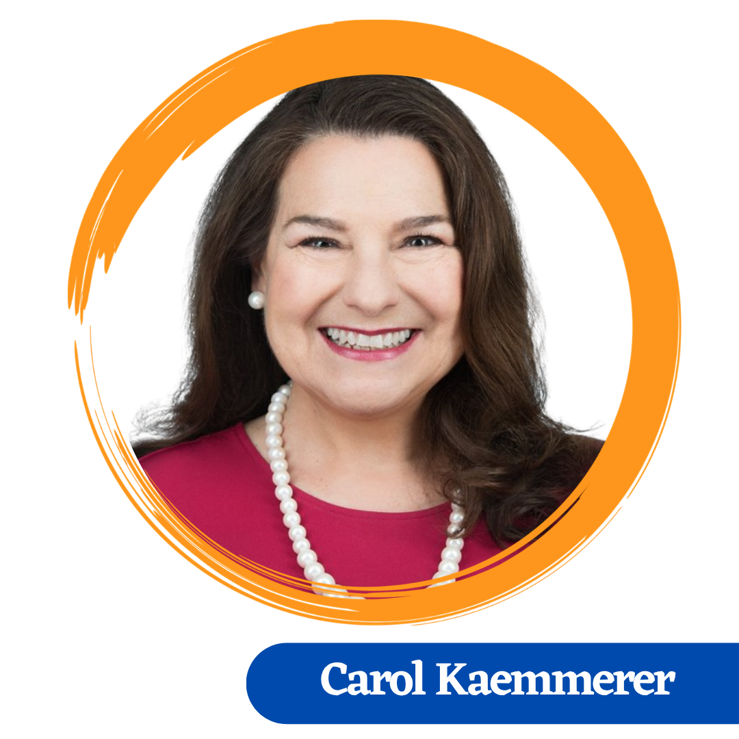 Carol has long brown hair slightly curled at the ends falling over the shoulder. She is smiling and wearing a pearly earring and necklace with a red colored top