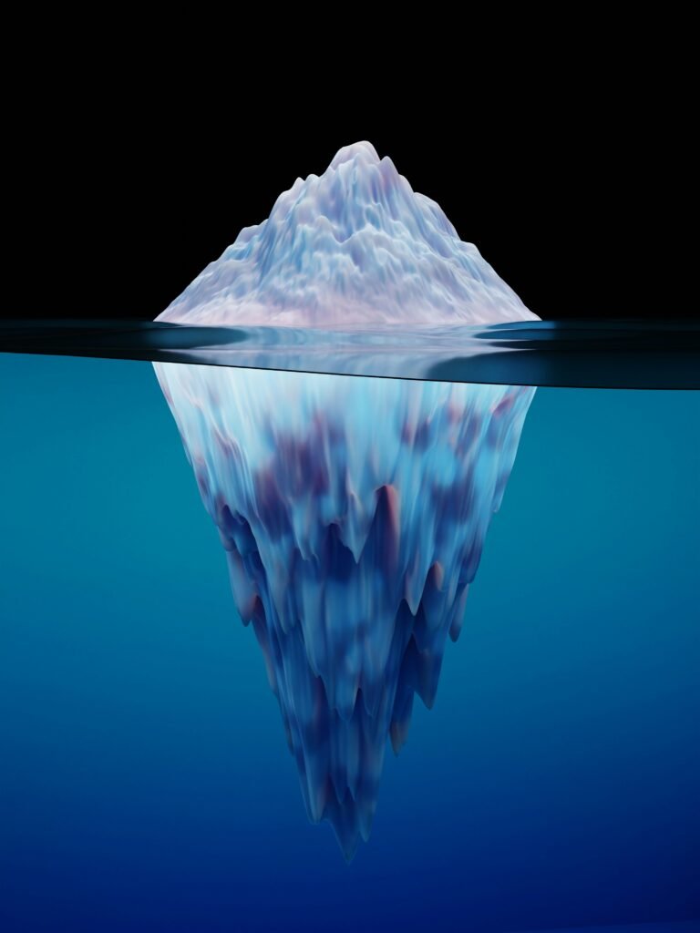Iceberg shaped like a triangle witha black background with its reflection shown under with the image inverted over a blue watery reflection. This indicates the problem is rarely seen at the first glance, yet the real issues lie deeper than surface values