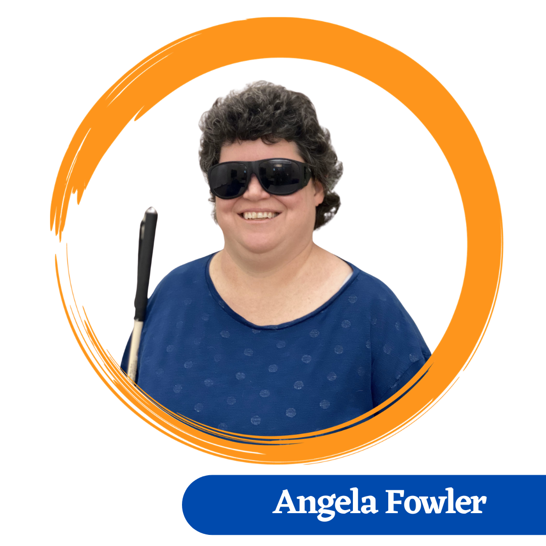 Headshot of Angela Fowler, is smiling and has dark wavy hair, wearing a blue patterned top and dark glasses and holding her vision cane.